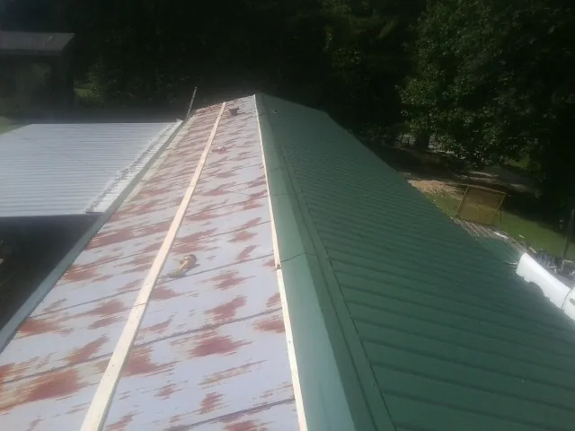 Old rusted panels beside newly installed green metal roofing — Wind Damage Roof Repair by Roofing Brothers in North Providence