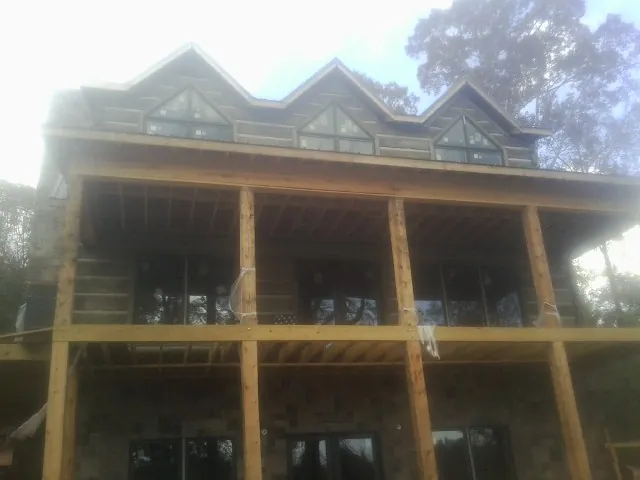 Dormers and porch framing on a large log home under construction — Roof Coating work by our crew in North Providence