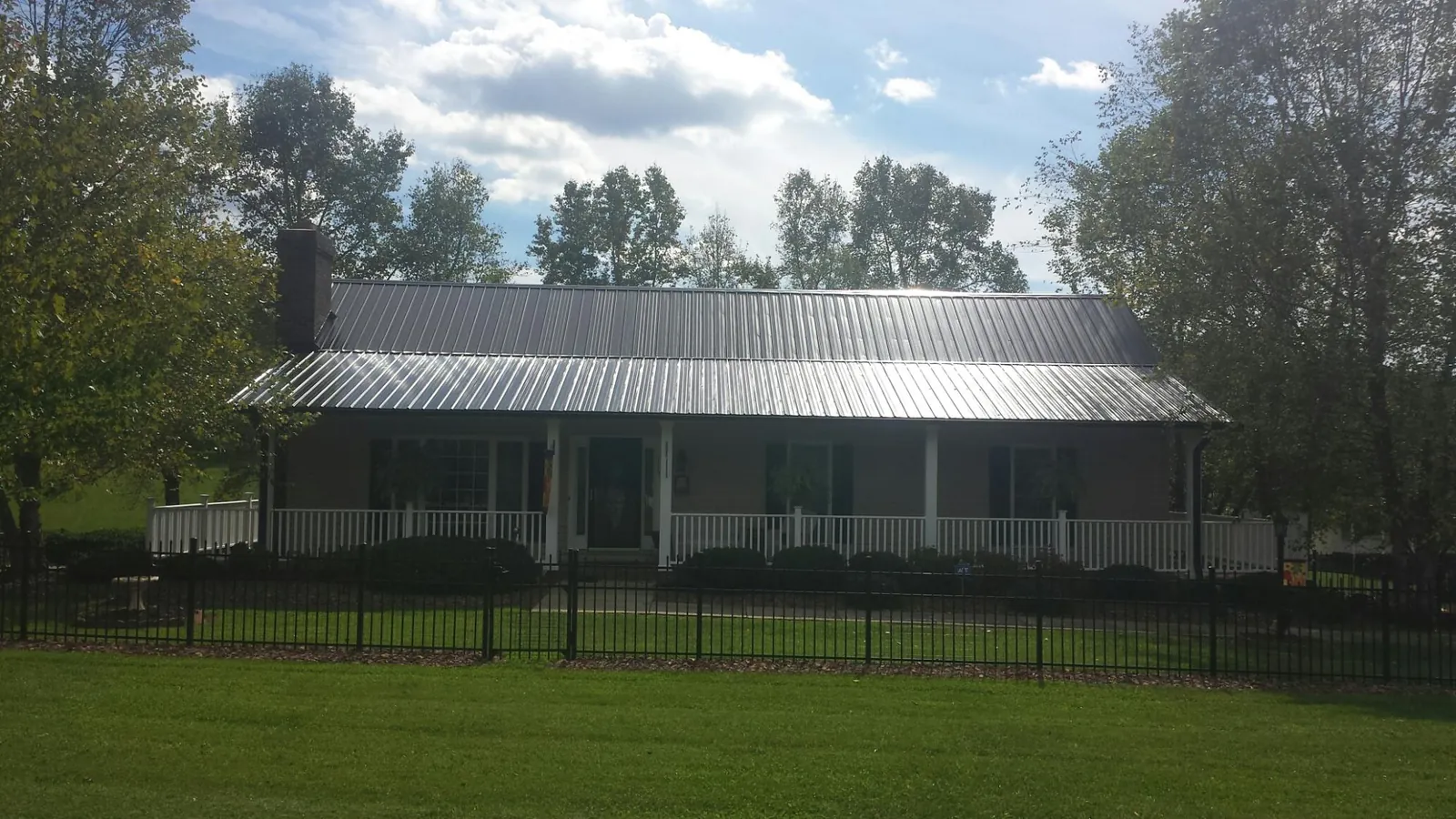 Gray metal roof on a brick ranch with a full width front porch — Gutter Guard Installation work by our crew in North Providence