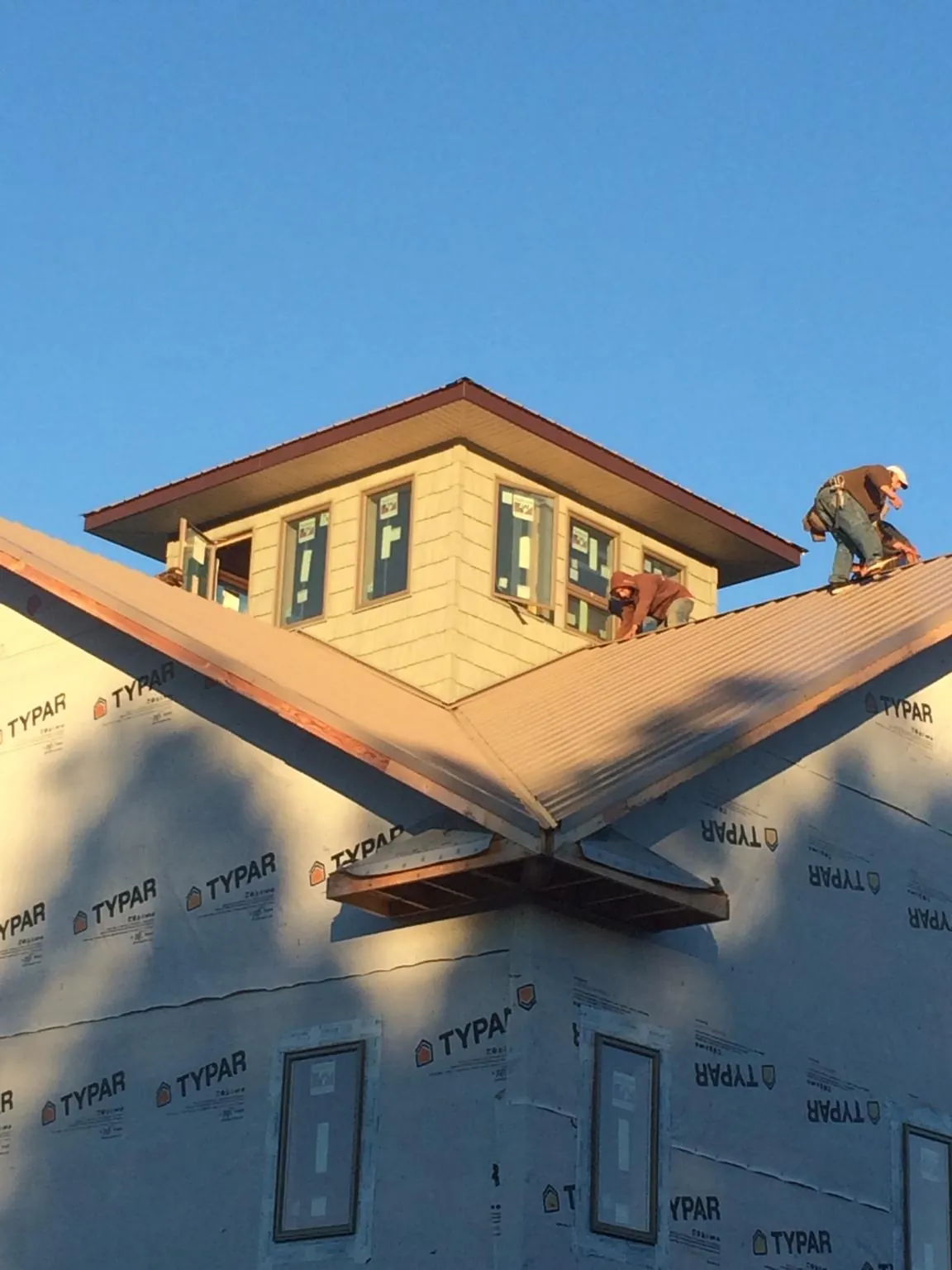 Roofers working around a rooftop cupola on a new metal roof at sunset — Roof Waterproofing in North Providence by Roofing Brothers
